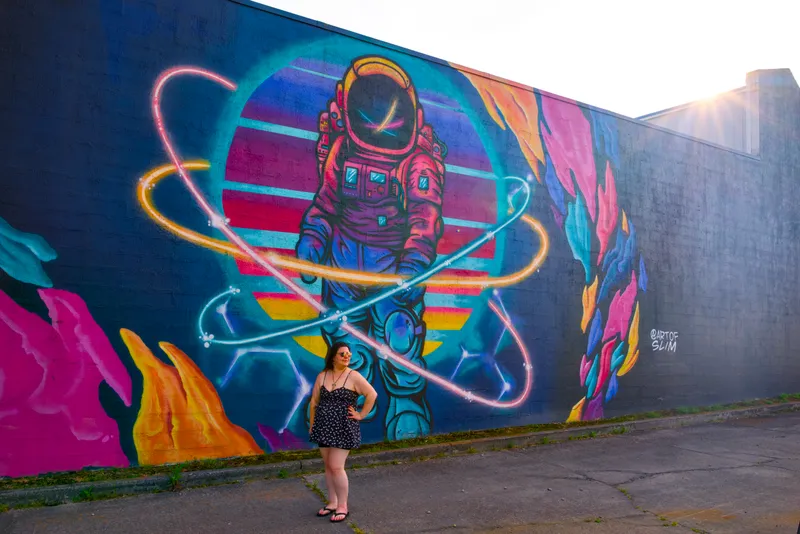 Brandi stands beneath a colorful astronaut mural.